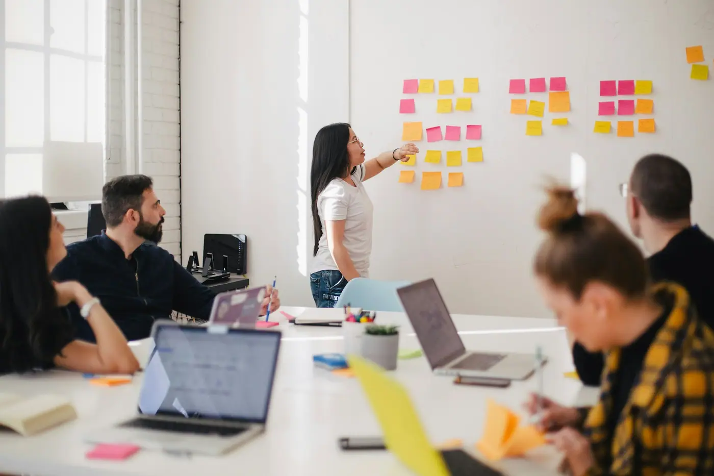 Profesional presentando ideas frente a un tablero con notas adhesivas durante una reunión de trabajo
