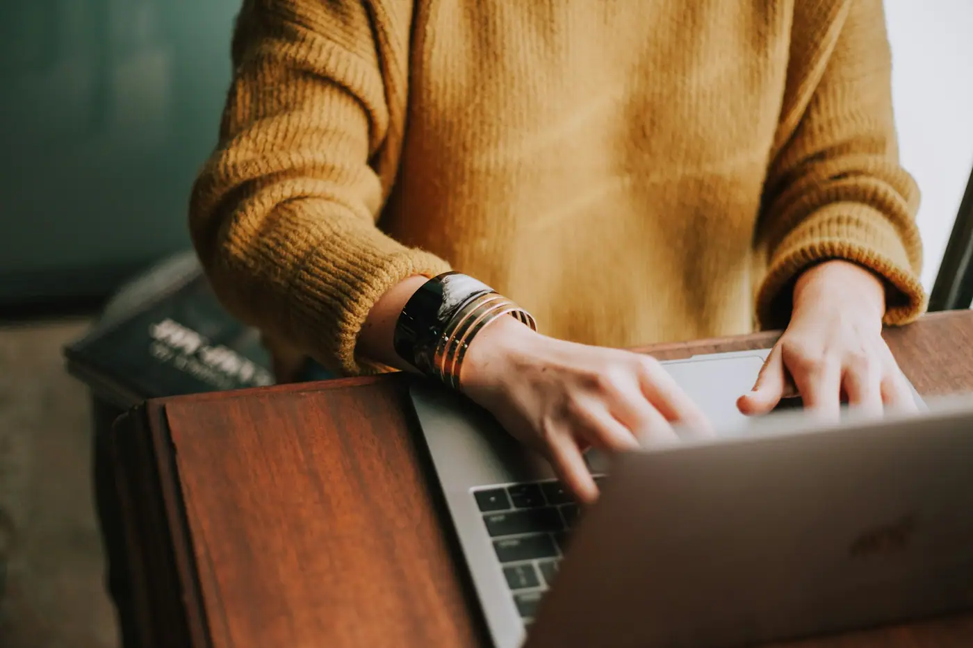 Persona escribiendo en una laptop sobre una mesa de madera
