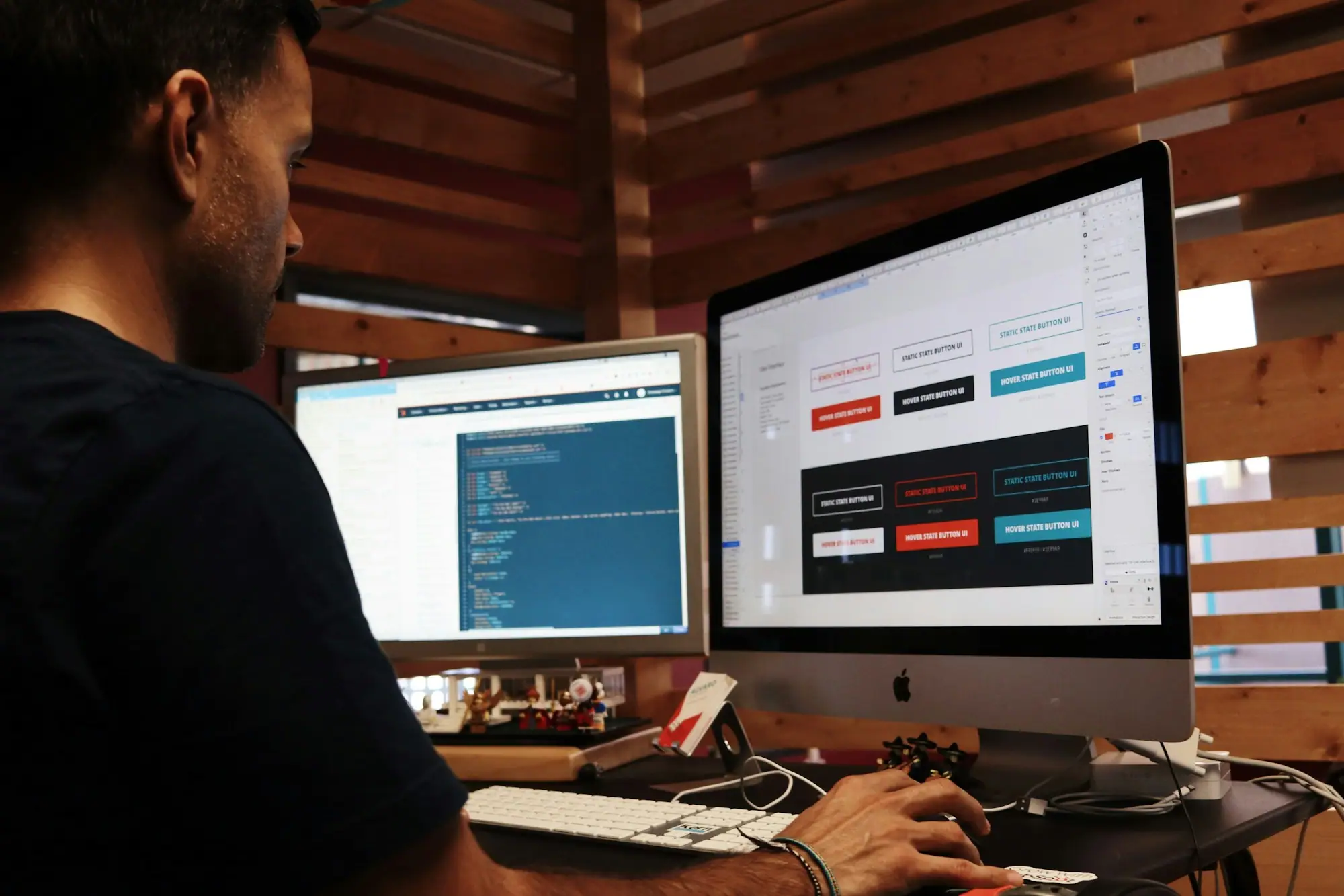 Diseñador trabajando frente a dos monitores con interfaces de un sitio web